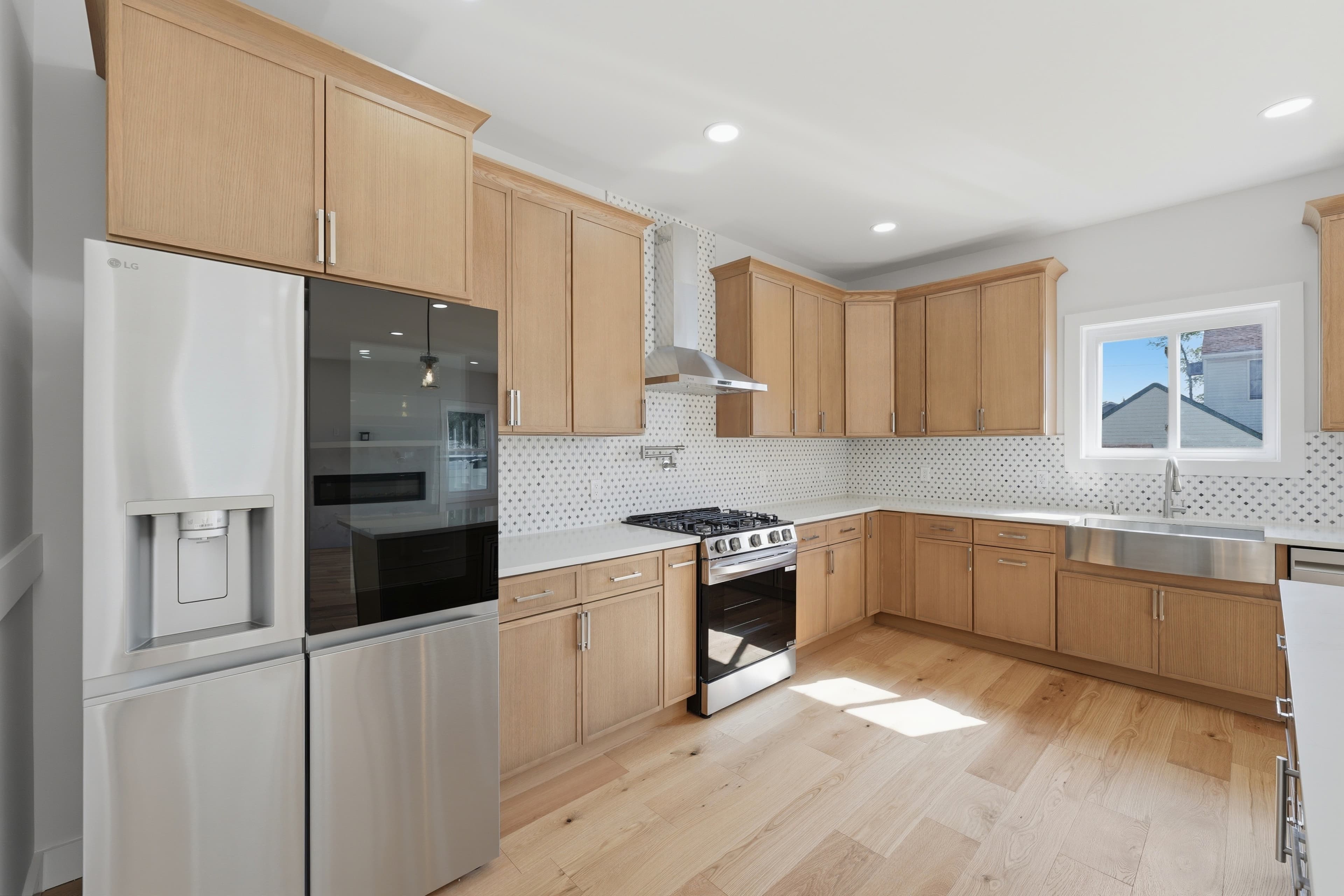Modern kitchen with light wood cabinets, stainless steel appliances, and a patterned tile backsplash.